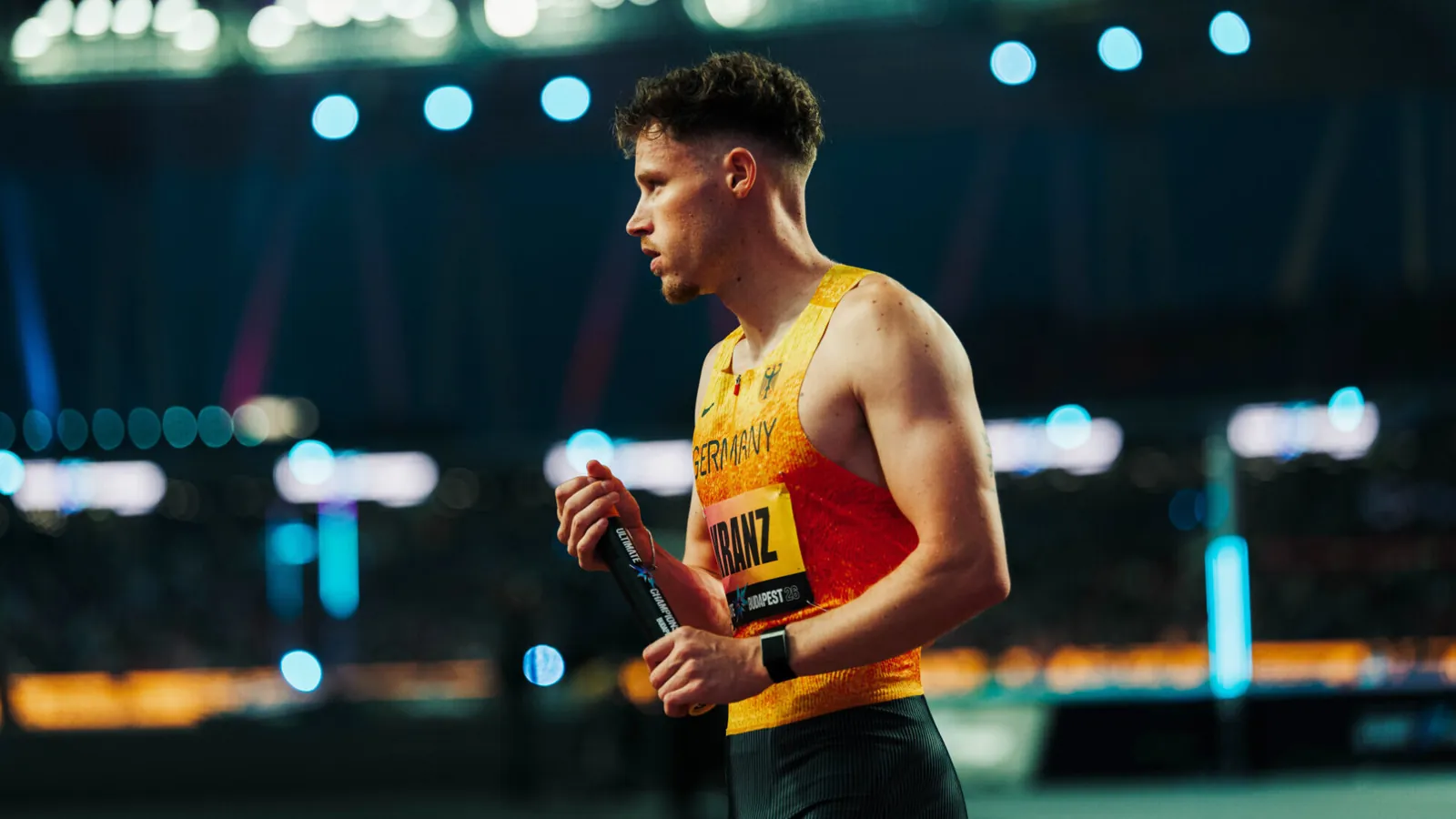 Der deutsche Sprinter Kevin Kranz konzentriert sich vor dem Start und hat einen Staffelstab in der Hand.